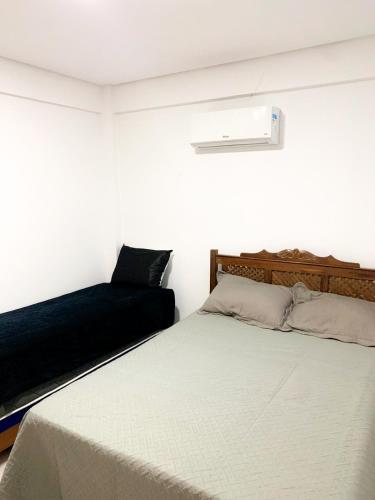 Cette chambre blanche dispose d'un lit et d'une lumière sur le mur. dans l'établissement Condomínio Primavera, à Itacaré