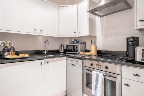 a kitchen with white cabinets and white appliances at Stay Kula London - Tower Bridge in London