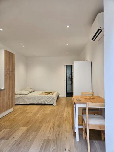 Cette chambre comprend deux lits, un bureau et une table. dans l'établissement Le Studio Cyprien, à Toulouse