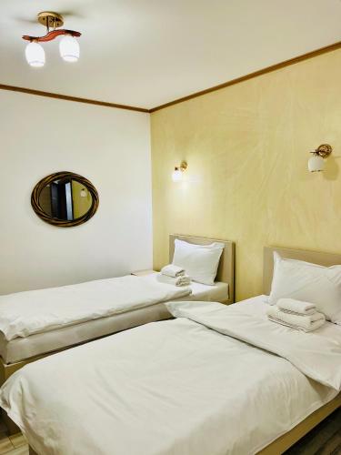 two beds in a room with a mirror on the wall at Hotel Marina srl in Bucharest