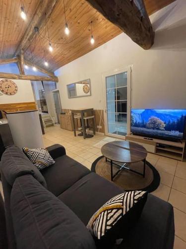 un salon avec un canapé et une télévision à écran plat dans l'établissement La Bergerie, à Thodure