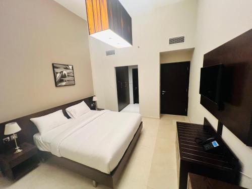 AlRaef Luxury Apartments في دبي: غرفة نوم بسرير ابيض وتلفزيون