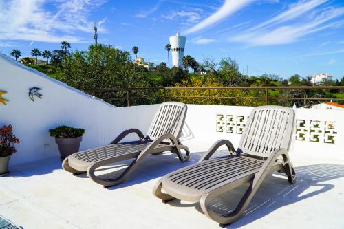 two white chairs sitting on a balcony with a lighthouse at Villa Marrachinho in Albufeira