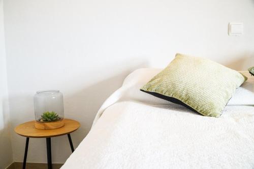 a bed with a pillow and a glass vase on a table at Villa Marrachinho in Albufeira