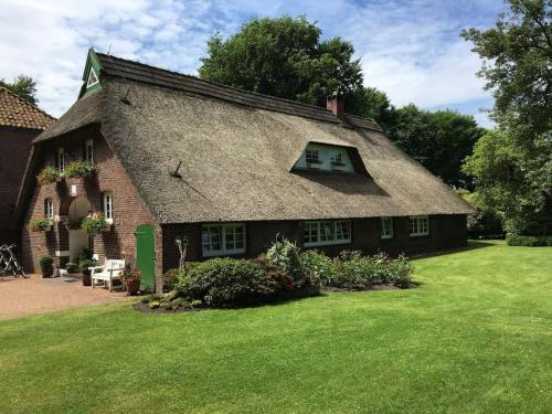 a large brick house with a grass yard at Idyllische Ferienwohnung in Wiefelstede in Wiefelstede