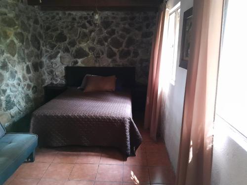 a bedroom with a bed in a stone wall at VILLA ELENA un refugio en el bosque in El Manzanillo