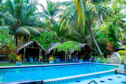 a swimming pool in front of a resort with palm trees at Mandavilla Airport Transit Hotel in Demanhandiya