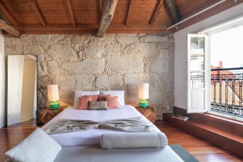a bedroom with a large bed and a stone wall at Bandeiras in Porto