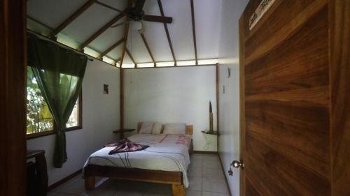 a bedroom with a bed in a room with a window at casa de los amigos caribena in Cahuita