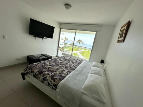 um quarto com uma cama grande e uma janela grande em VISTAMAR PARACAS Depa de playa la mejor vista em Paracas