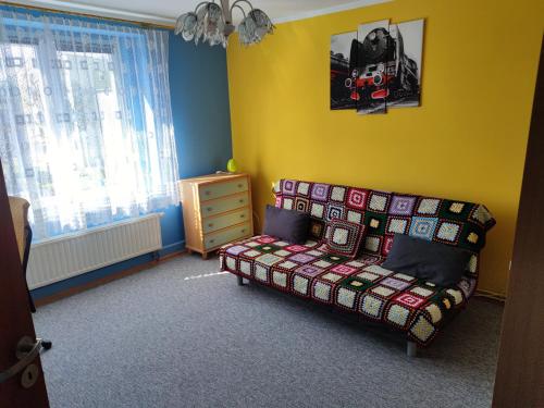ein Schlafzimmer mit einem Sofa in einem Zimmer mit gelben Wänden in der Unterkunft Apartament Jaśminów in Ruda Śląska