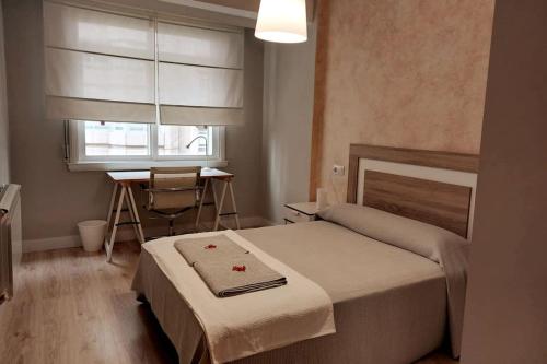 a bedroom with a bed and a desk and a window at Piso familiar zona estación tren- bus-4 caminos in A Coruña
