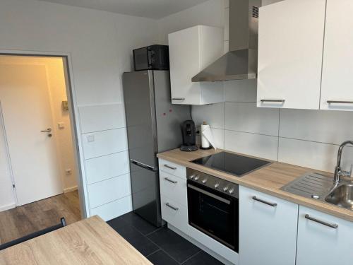 eine Küche mit weißen Schränken, einer Spüle und einem Kühlschrank in der Unterkunft Ferienwohnung Lippstadt in Lippstadt