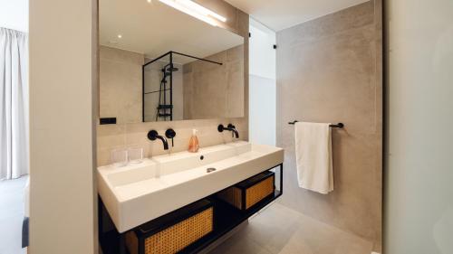 a bathroom with a white sink and a mirror at The Wharf Luxury Apartment MT 7E in Willemstad