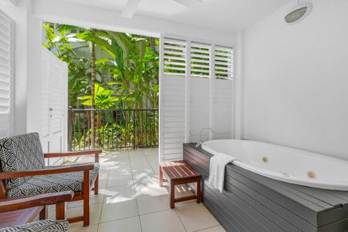 a bathroom with a bath tub and a patio at Elysium The Beach Club in Palm Cove