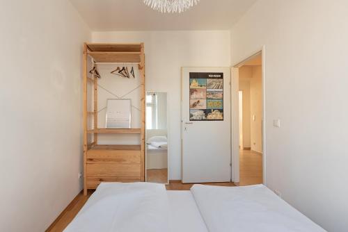 ein weißes Schlafzimmer mit einem Bett und einem Spiegel in der Unterkunft Zentral und ruhig bei Schönbrunn in Wien