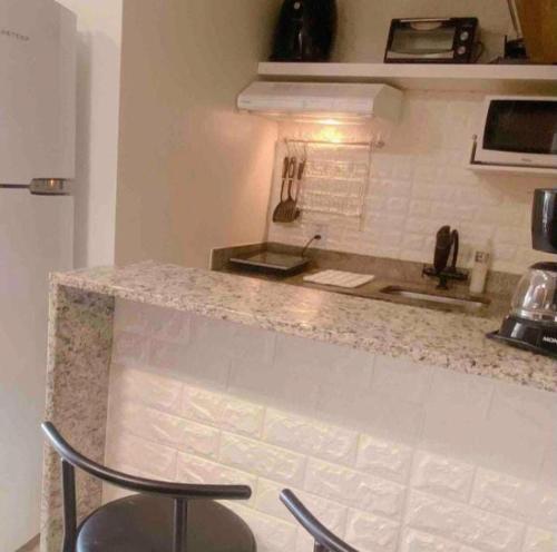 a kitchen with a counter with two stools next to it at Belo Flat Resort Lake Side Beira Lago in Brasilia