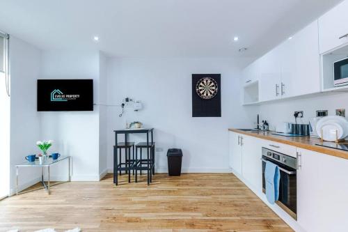 a kitchen with white cabinets and a wooden floor at Stylish Media City Apartment, Sleeps 3, Darts Board, Smart TV, Tram Stop, Long Term Disc in Manchester