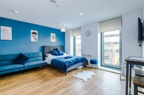 a blue bedroom with a bed and a couch at Stylish Media City Apartment, Sleeps 3, Darts Board, Smart TV, Tram Stop, Long Term Disc in Manchester