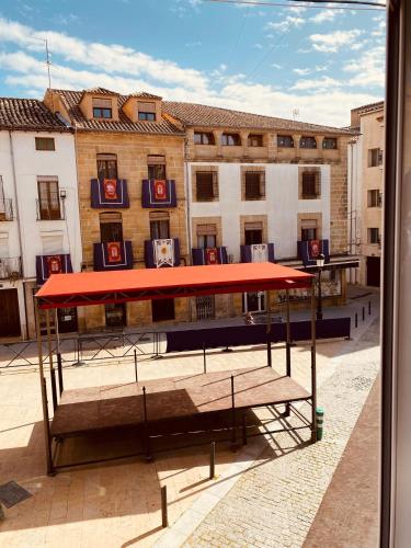 a bus stop with a red roof in front of a building at El ventanal del viajero in Baeza