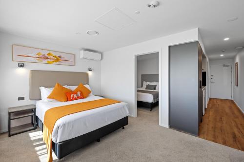 a bedroom with a large bed with orange pillows at Golden Hotel in Christchurch