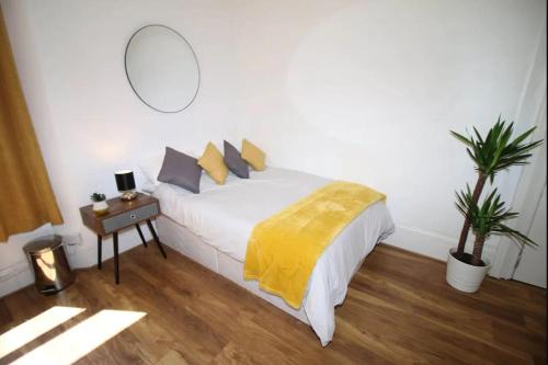 a bedroom with a white bed with a yellow blanket at Big Value Bedsit by Property Promise in Cardiff