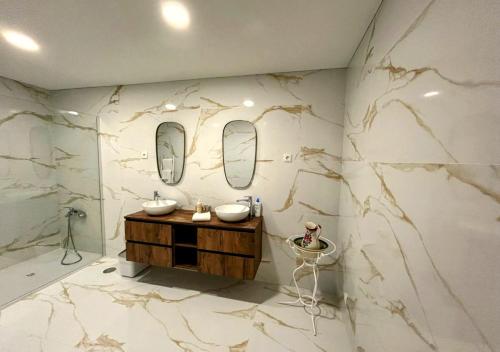 a bathroom with a marble wall with two sinks and mirrors at Casa by Anita Guesthouse in Esposende