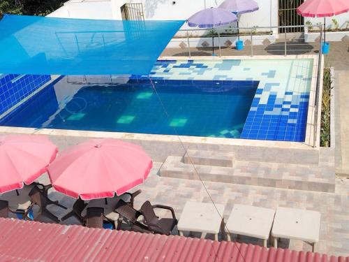 Dois guarda-sóis e cadeiras cor-de-rosa junto a uma piscina em Hotel Palmetto Beach Coveñas em Coveñas
