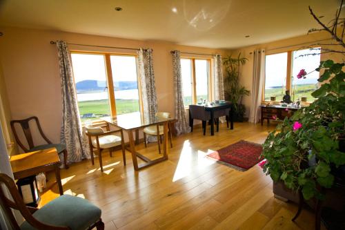 a living room with a table and chairs and windows at Rysa House B&B in Stromness