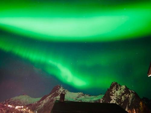 una imagen de la aurora boreal en el cielo sobre las montañas en 3-roms leilighet, Svolvær, Lofoten, en Svolvær