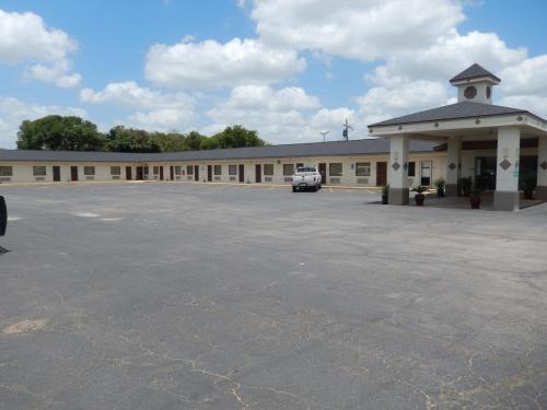 a large building with a parking lot in front of it at Pearsall Executive Inn in Pearsall