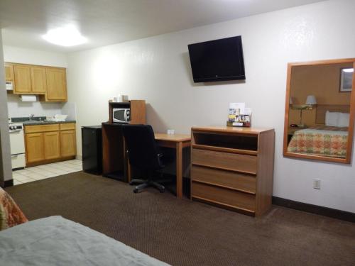 a room with a desk and a bed and a mirror at Pearsall Executive Inn in Pearsall
