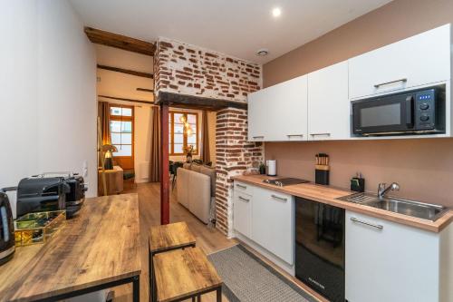 a kitchen with white cabinets and a brick wall at Appartement typique hyper centre Albi - Neuf Premium - Parking gratuit in Albi