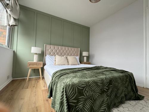 a bedroom with a large bed with a green wall at Grace House - 15 Minutes To Central London in Thamesmead