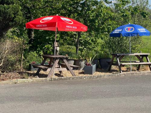 two picnic tables and an umbrella on the side of the road at Hazeldene Hotel in Gretna Green