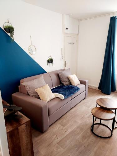 uma sala de estar com um sofá e uma parede azul em Studio B aux pieds des Thermes em Néris-les-Bains
