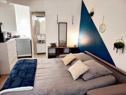 een slaapkamer met een groot bed met een blauwe accentmuur bij Studio B aux pieds des Thermes in Néris-les-Bains