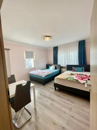 a room with two beds and a table and a chair at Leo Apartment Zentrum Rüsselsheim in Falkenberg