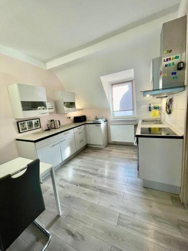 a kitchen with white cabinets and a wooden floor at Leo Apartment Zentrum Rüsselsheim in Falkenberg