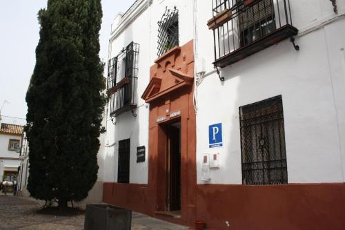 a building with a door and a tree on a street at PENSION CIBELES in Córdoba