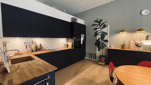 a kitchen with black cabinets and a wooden table at ApartmentInCopenhagen Apartment 1595 in Copenhagen