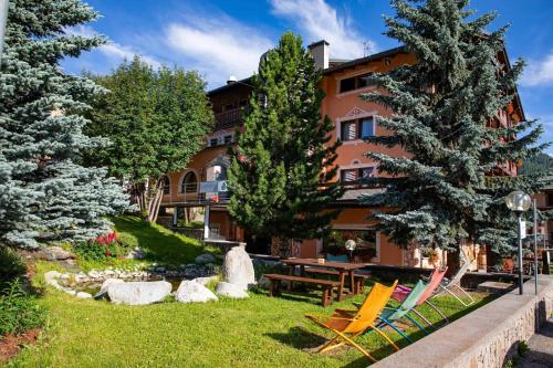 a resort with chairs and a table and trees at Hotel Galli in Livigno