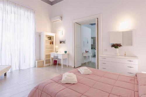 una camera bianca con letto rosa e scrivania di Gli Appartamenti della Villa a Santa Maria Capua Vetere