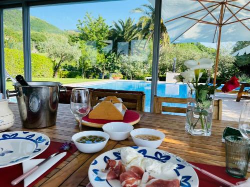une table en bois avec des assiettes de nourriture et une piscine dans l'établissement Villa Mandetta B&B, à Santo Stefano del Sole