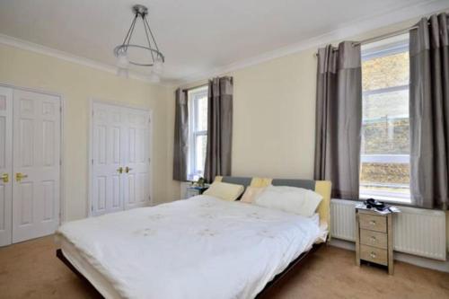 1 dormitorio con 1 cama blanca grande y 2 ventanas en Luxury 3 bedroom, 3 bath apt by Oxford St & Soho, en Londres
