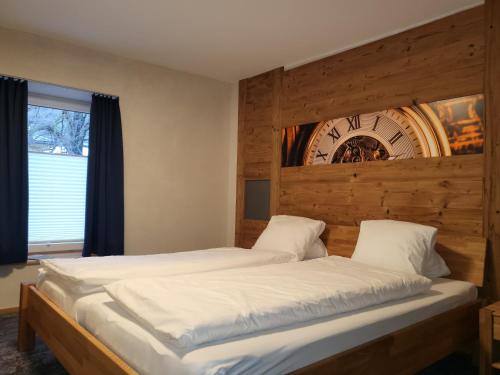 a bedroom with two beds with a clock on the wall at Kapitel 7 Boutique-Hotel in Raron