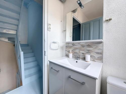 a bathroom with a sink and a mirror and stairs at Maison La Petite Bleue - Balcon - Wifi Fibre - Menage inclus in Tarbes
