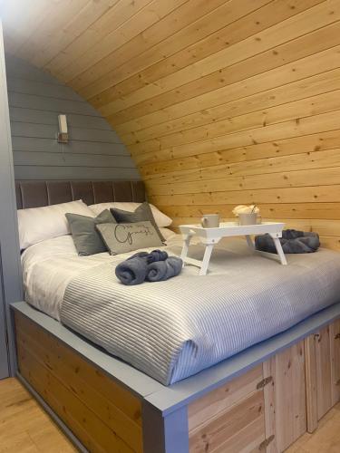 a bed in a wooden room with a table on it at Loch View Luxury Pod in Connel