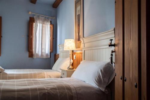 1 dormitorio con 2 camas, paredes azules y lámpara en Apartamento Turístico El Sotanillo de Valverde de la Vera, en Valverde de la Vera