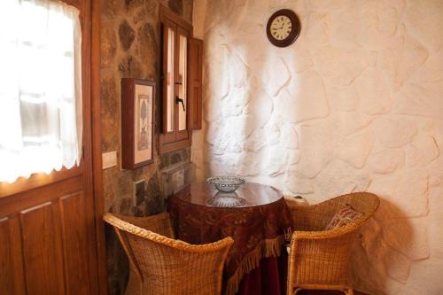 a table in a room with two chairs and a clock at Apartamento Turístico El Sotanillo de Valverde de la Vera in Valverde de la Vera